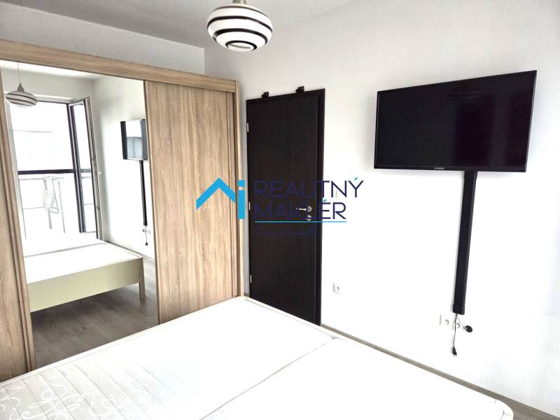 A bedroom with a TV, a wardrobe, and wooden doors in a studio apartment.