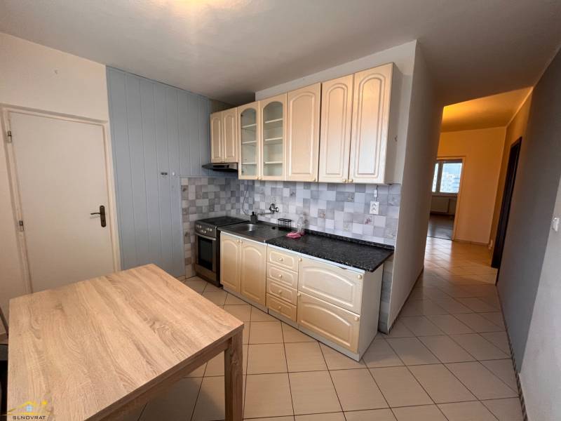 Kitchen in a 2-room apartment with tiled flooring and a wooden decor table.