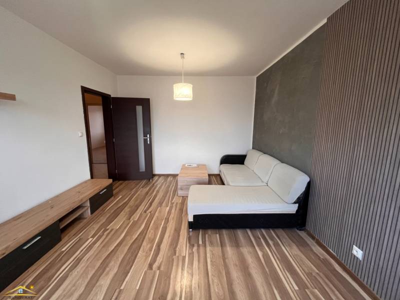 Living room with a sofa and wood-patterned flooring in a two-room apartment.