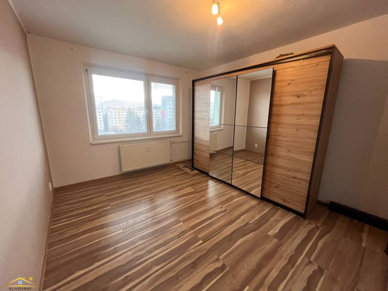 A room in a 2-room apartment with a wooden decor floor and a built-in wardrobe.