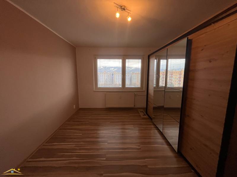 A room with a wooden decor floor and a large built-in wardrobe in a 2-room apartment.