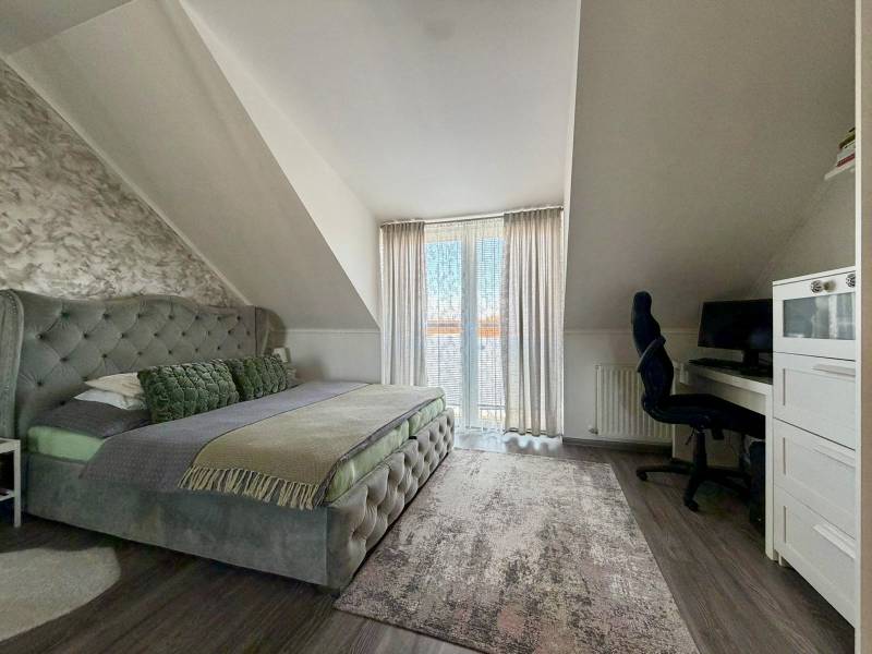 Bedroom in a two-room apartment with a double bed, a desk, and a floor with a wooden decor.