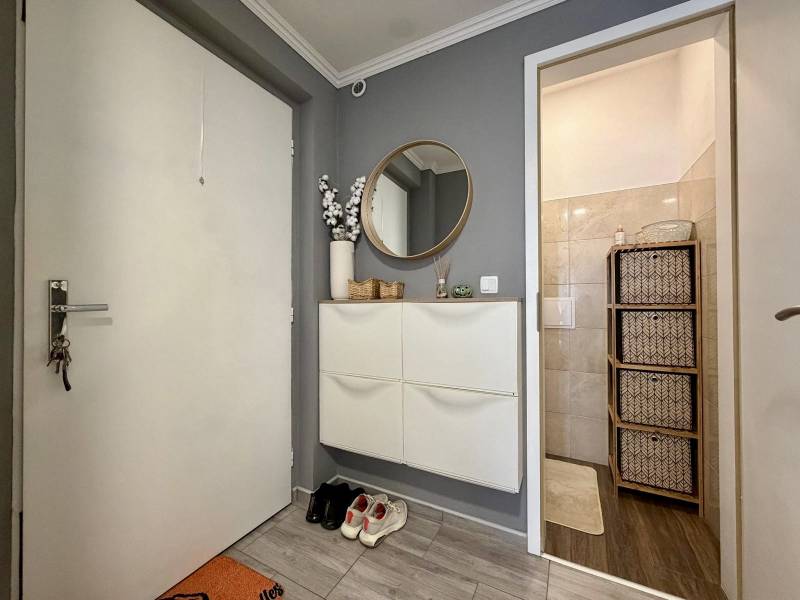 Hallway in a 2-room apartment with a wall mirror and a shoe cabinet, entrance to the bathroom.