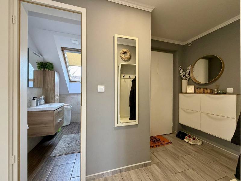 A hallway with a wooden decor floor, a mirror, and a bathroom in a 2-room apartment.