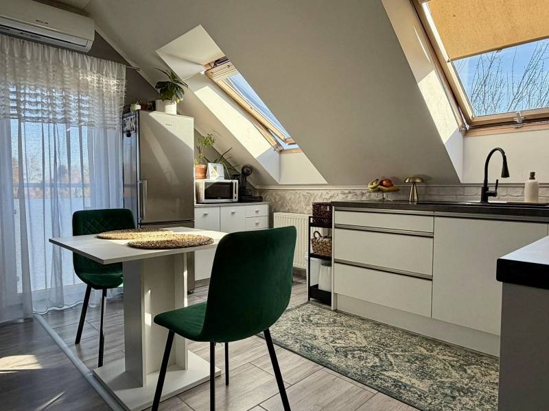 Kitchen in a 2-room apartment with slanted ceilings, skylights, and furniture.