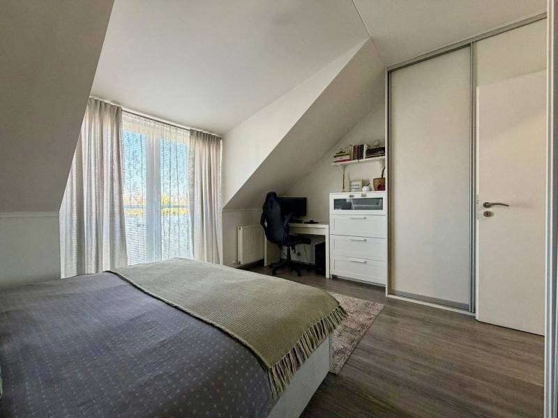 Bedroom in a two-room apartment with a desk and a wooden decor floor.