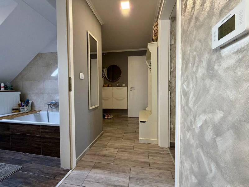 Bathroom in a two-room apartment with a wooden decor floor and light walls.
