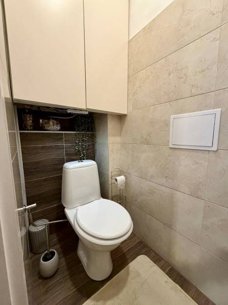 A toilet with a wooden decor floor in a 2-room apartment.