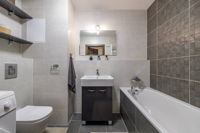 Bathroom in a 3-room apartment with a bathtub, a cabinet under the sink, and a washing machine.