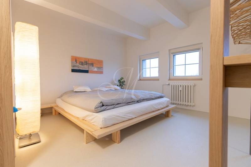 Bedroom of a 3-room apartment with a bed, lamp, and picture on the wall.