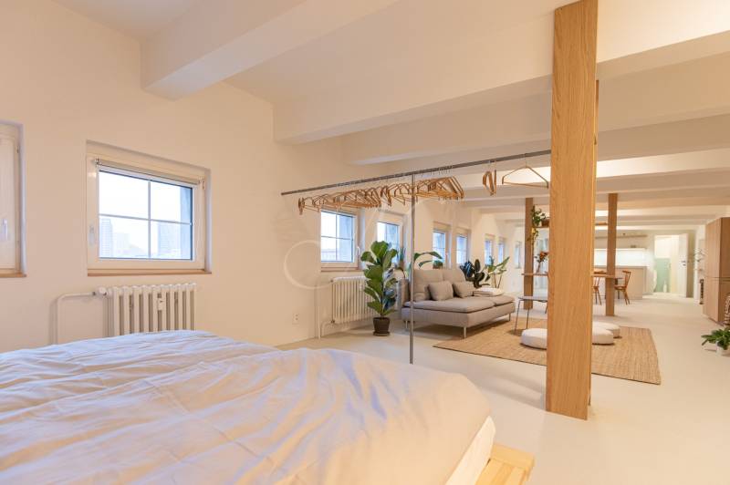 Spacious interior of a 3-room apartment with a bed, coat racks, and a sofa set.