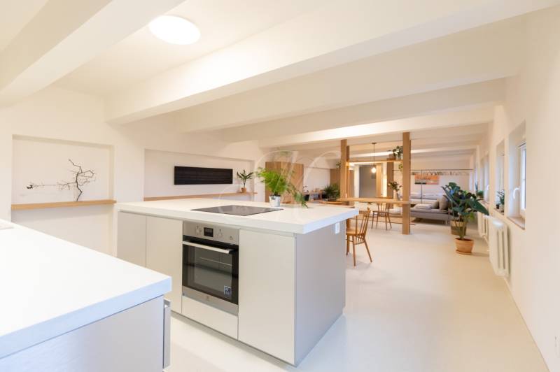 A bright kitchen with an island in a 3-room apartment, white surfaces, wooden furniture decor.