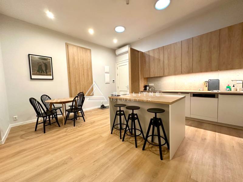 A kitchen with a bar counter, dining table, and a floor with a wood decor in a 2-room apartment.