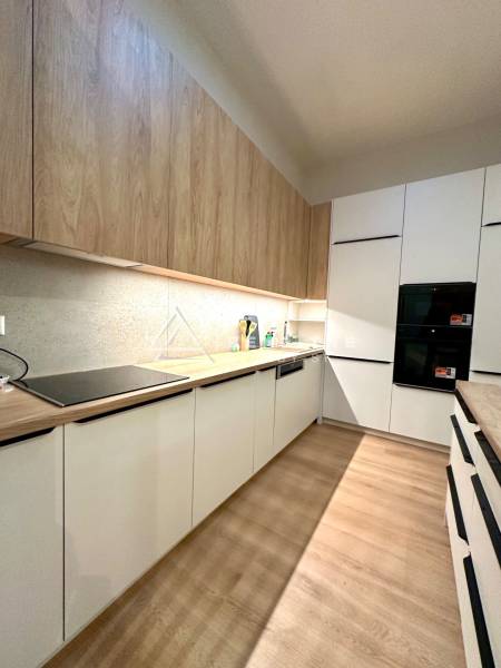 A kitchen with built-in appliances and a wooden decor floor in a 2-room apartment.