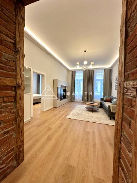 Living room in a two-room apartment with a wooden decor floor and a brick wall.