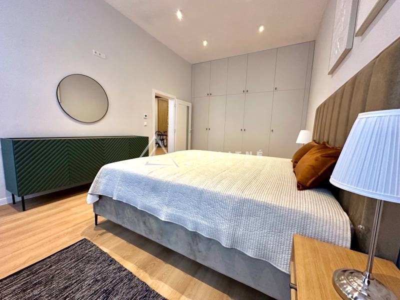 Bedroom in a two-room apartment with a bed, wardrobes, and a floor with a wooden decor.