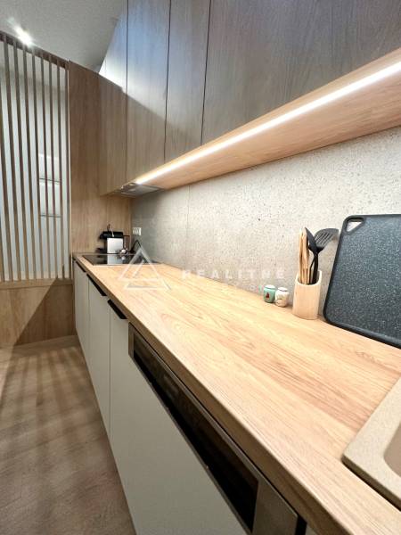 A kitchen unit in a 2-room apartment with a wooden decor and built-in appliances.