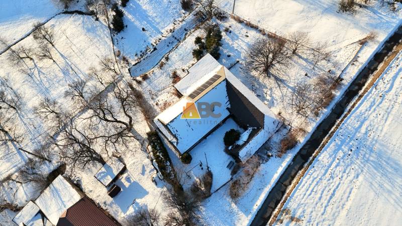 A snow-covered cottage on Zánemecká Street in Hriňová surrounded by trees and nature.