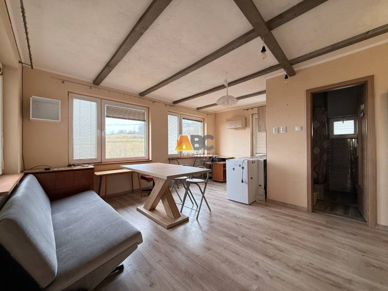 The interior of a cabin with a wooden decor floor, a table, and a couch.