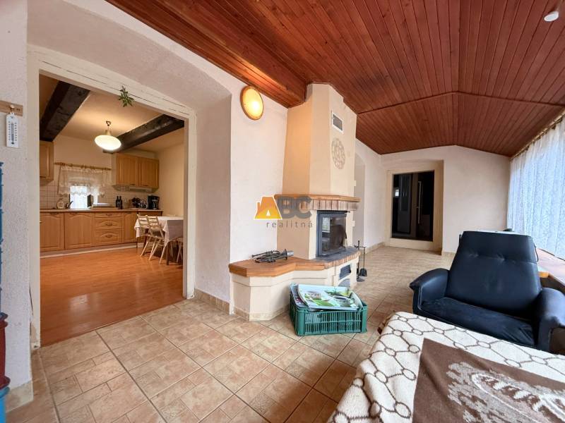 A cottage with a fireplace and a wooden decor floor, connected to the dining room and kitchen.