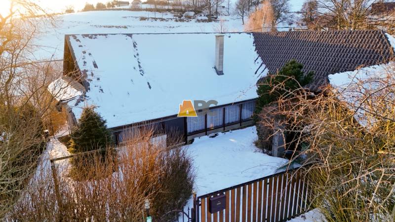 A cottage in a snowy landscape on Zánemecká Street in Hriňová, surrounded by trees.