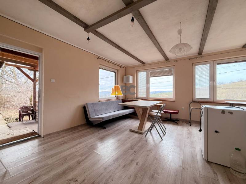 Interior of a cabin with seating, a view of nature, and a floor with a wooden decor.