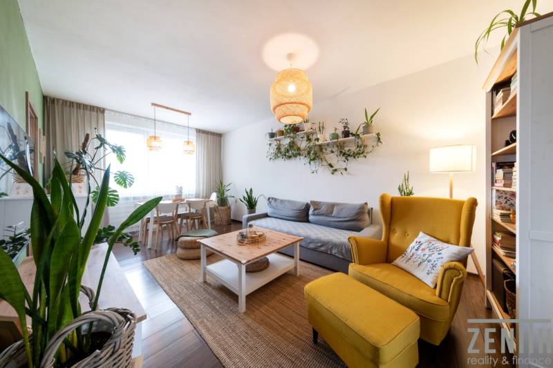 Living room in a 3-room apartment with plants, a yellow armchair, and a wooden decor floor.