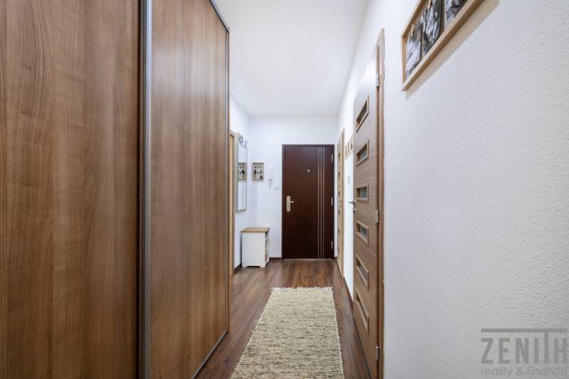 A hallway in a 3-room apartment with a wooden decor floor and built-in wardrobes.