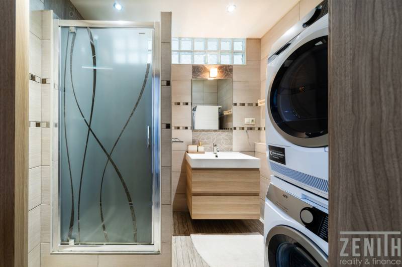 A bathroom with a sink, shower, and washing machine in a 3-room apartment.
