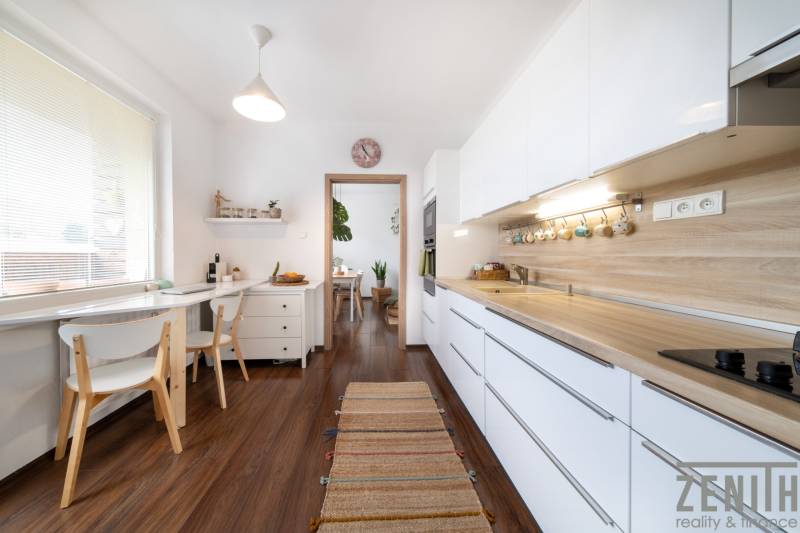 A kitchen in a 3-room apartment with white cabinets and a wood-patterned floor.