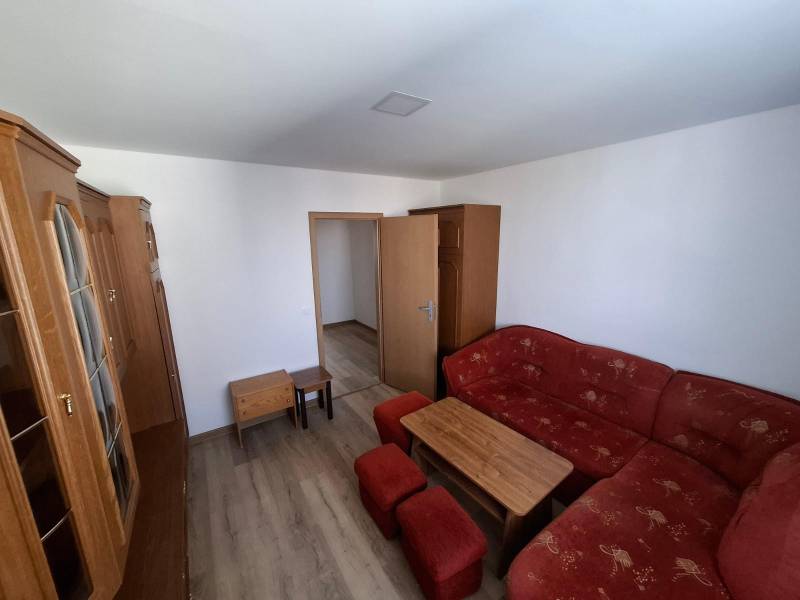 Living room in a 5 or more room apartment with a red sofa and a floor with a wood decor.