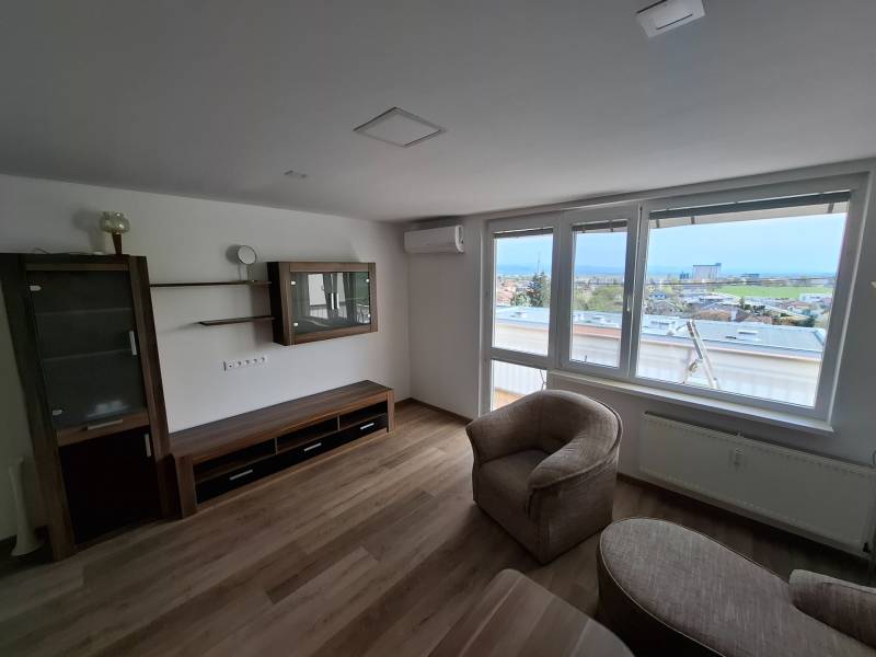 Living room with wood-patterned flooring and a comfortable armchair in a five or more room apartment.