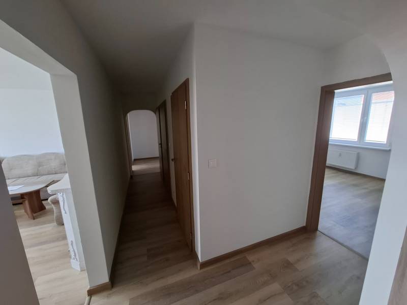 A hallway with a wooden decor floor in a 5 or more room apartment, entrance to the rooms.