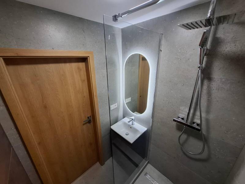 A bathroom in a 5 or more room apartment with an economical shower cabin and lighting.