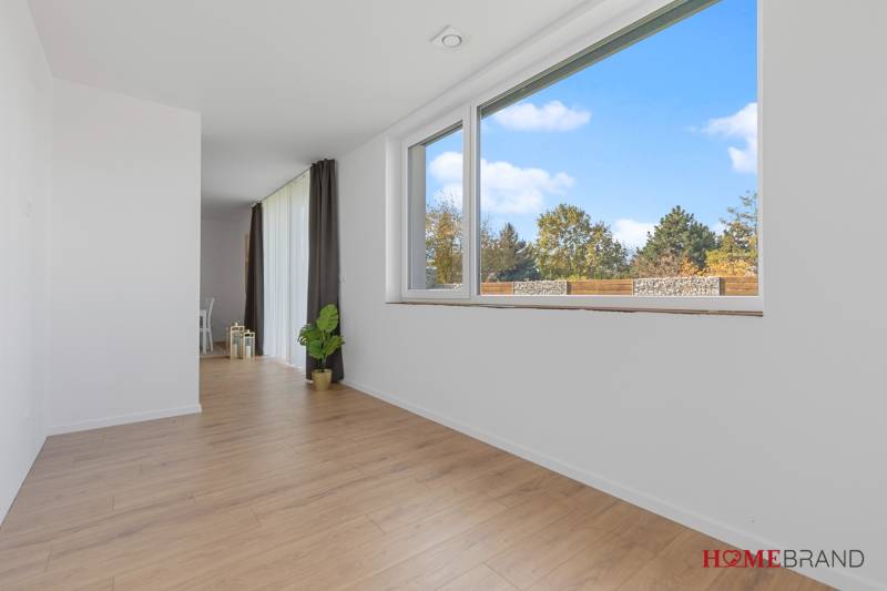 A spacious interior of a 3-room apartment with wooden decor flooring and large windows.