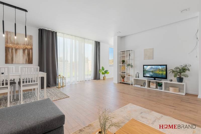 Living room in a three-room apartment with a wooden decor floor, dining area, and television.