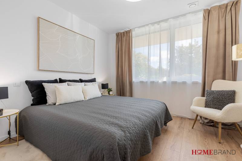 A bedroom in a 3-room apartment with a bed, an armchair, and a wooden decor floor.