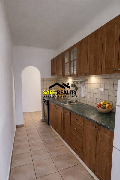 A narrow kitchen in a 2-room apartment with wooden cabinet decor and an arched doorway.