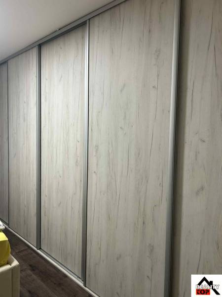 Sliding wooden wardrobe with a floor featuring a wooden decor in a 3-room apartment.