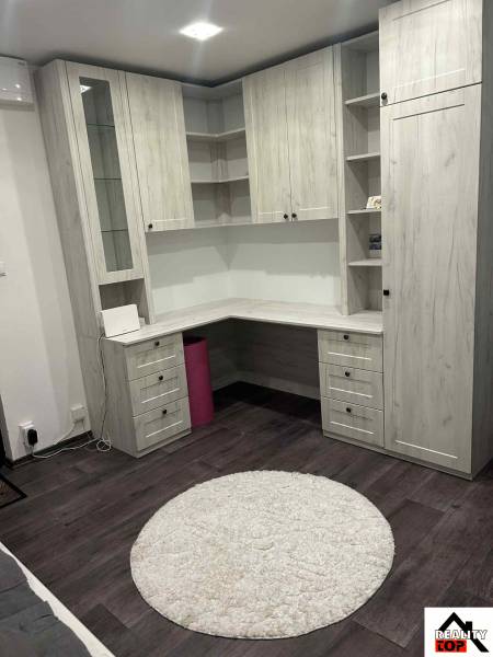 Interior of a 3-room apartment with a work corner, built-in furniture, and flooring with a wood decor.