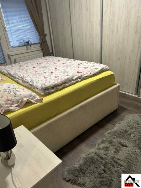 A bedroom in a 3-room apartment with a solid wood bed, a wardrobe, and a floor with a wooden decor.