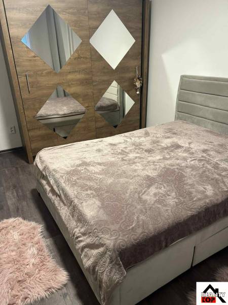 Bedroom of a 3-room apartment with a bed and a mirrored wardrobe on a wooden decor floor.