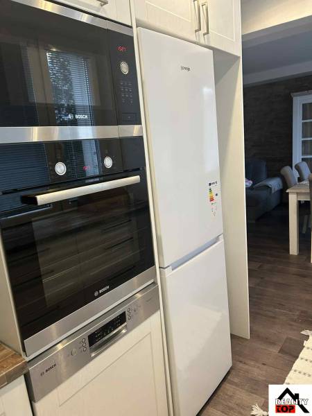 A kitchen in a 3-room apartment with modern appliances and a wooden decor floor.