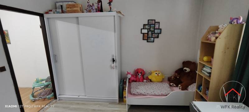Children's room in a 3-room apartment with a white wardrobe, bed, and toys.