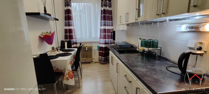 A kitchen in a 3-room apartment with a wooden decor floor and a dining table.