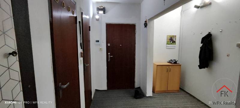 Entrance hallway with a wardrobe and a mirror in a 3-room apartment, floor with wood decor.
