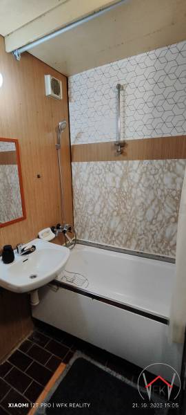 Bathroom in a 3-room apartment with a bathtub, sink, and tiles with a wooden decor.