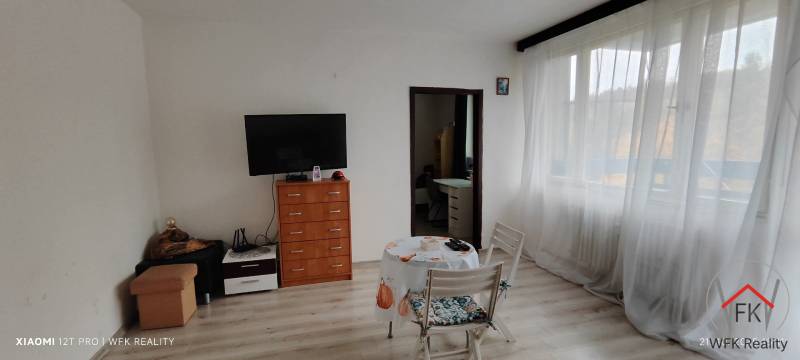 Living room in a 3-room apartment with a TV on a dresser and a table with two chairs.