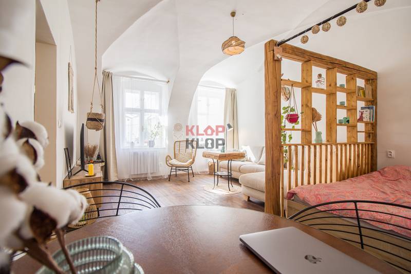 Interior of a 1-room apartment with a wood-decor floor, light, and cozy furniture.