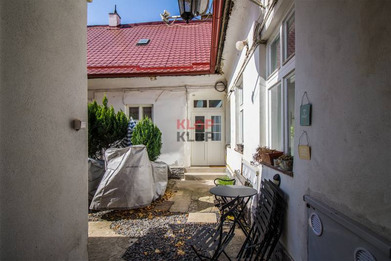Entrance to the courtyard, colorful walls, flowers, chairs, and table. Obchodná, Bratislava - Old Town.